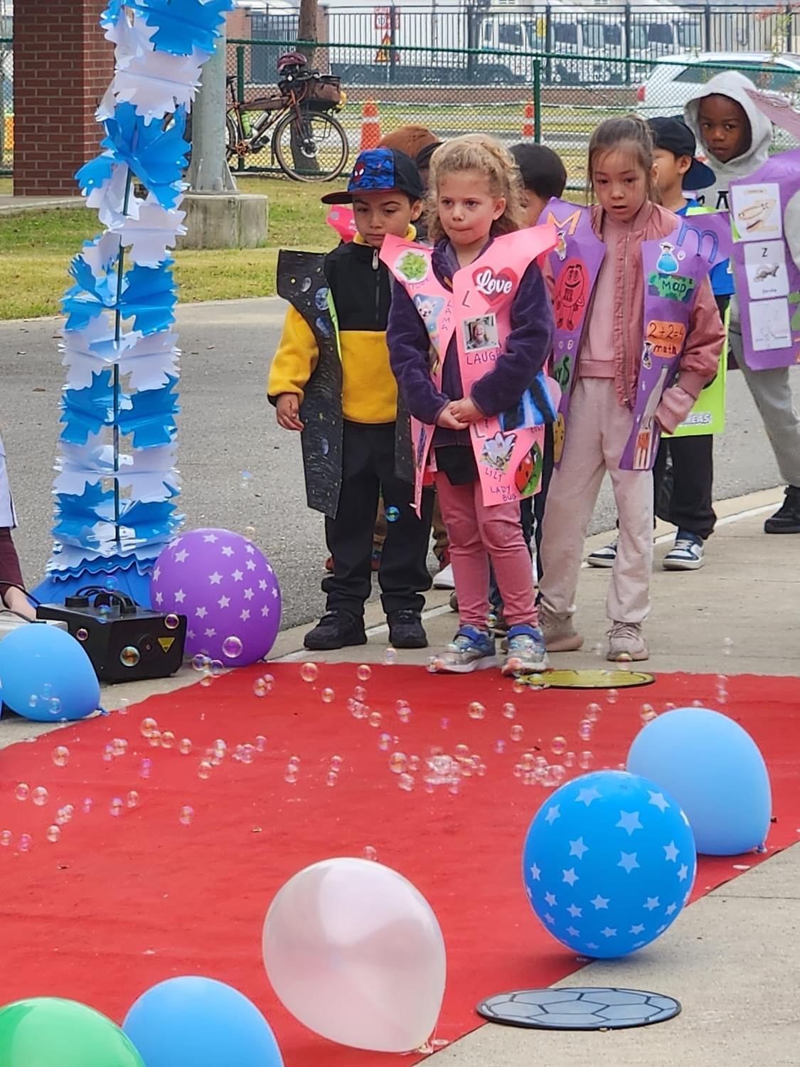 Kindergarten students anticipating their turn to walk down the red carpet to model their letter vest at Humphreys West Elementary School